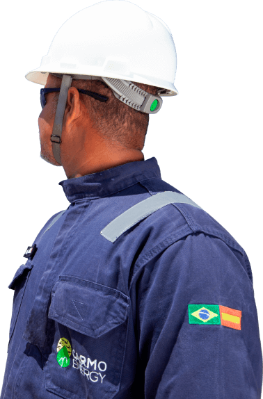 Funcionário com o uniforme azul escuro da Carmo Energy, olhando para trás com um capacete branco.